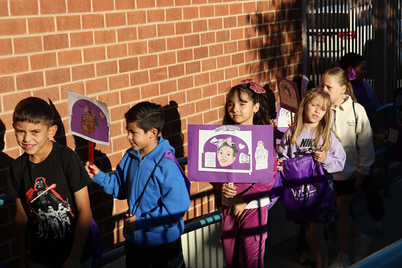 Students stand in a line, holding up handmade signs