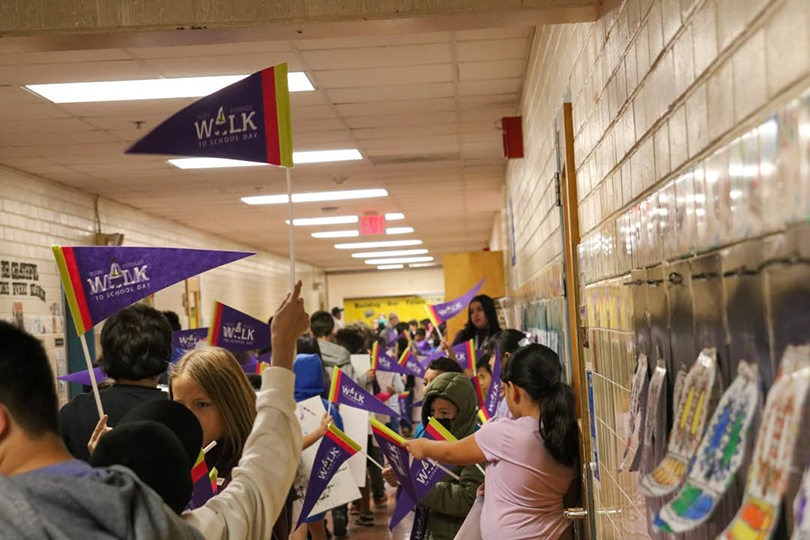 Students stand in the hallway, holding up purple Ruby Bridges pennants