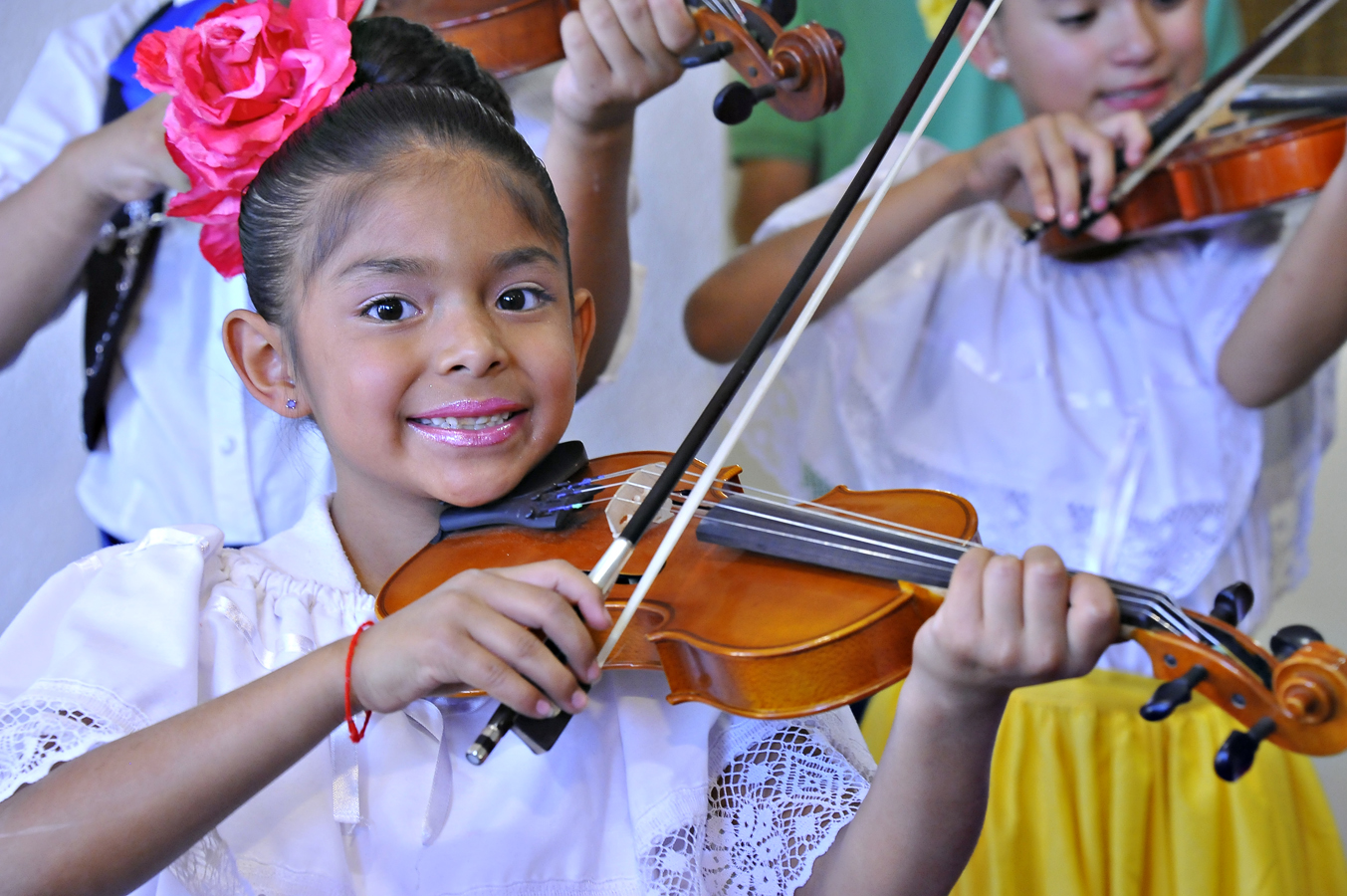 A little girl plays violin during a mariachi performance